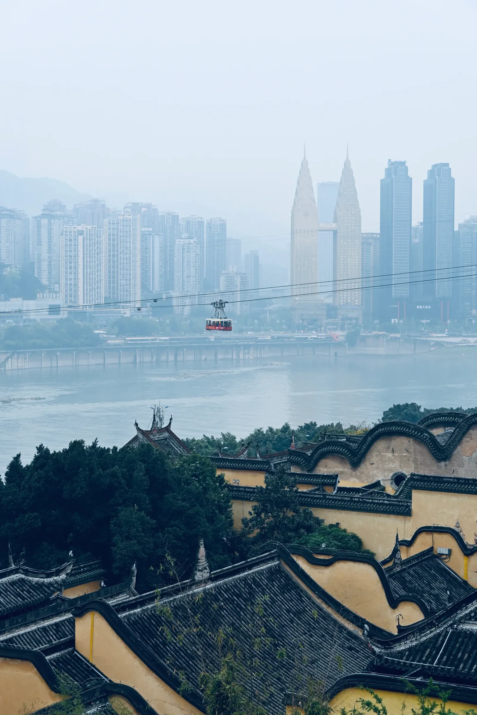 A hazy river skyline beyond traditional tiled rooftops.