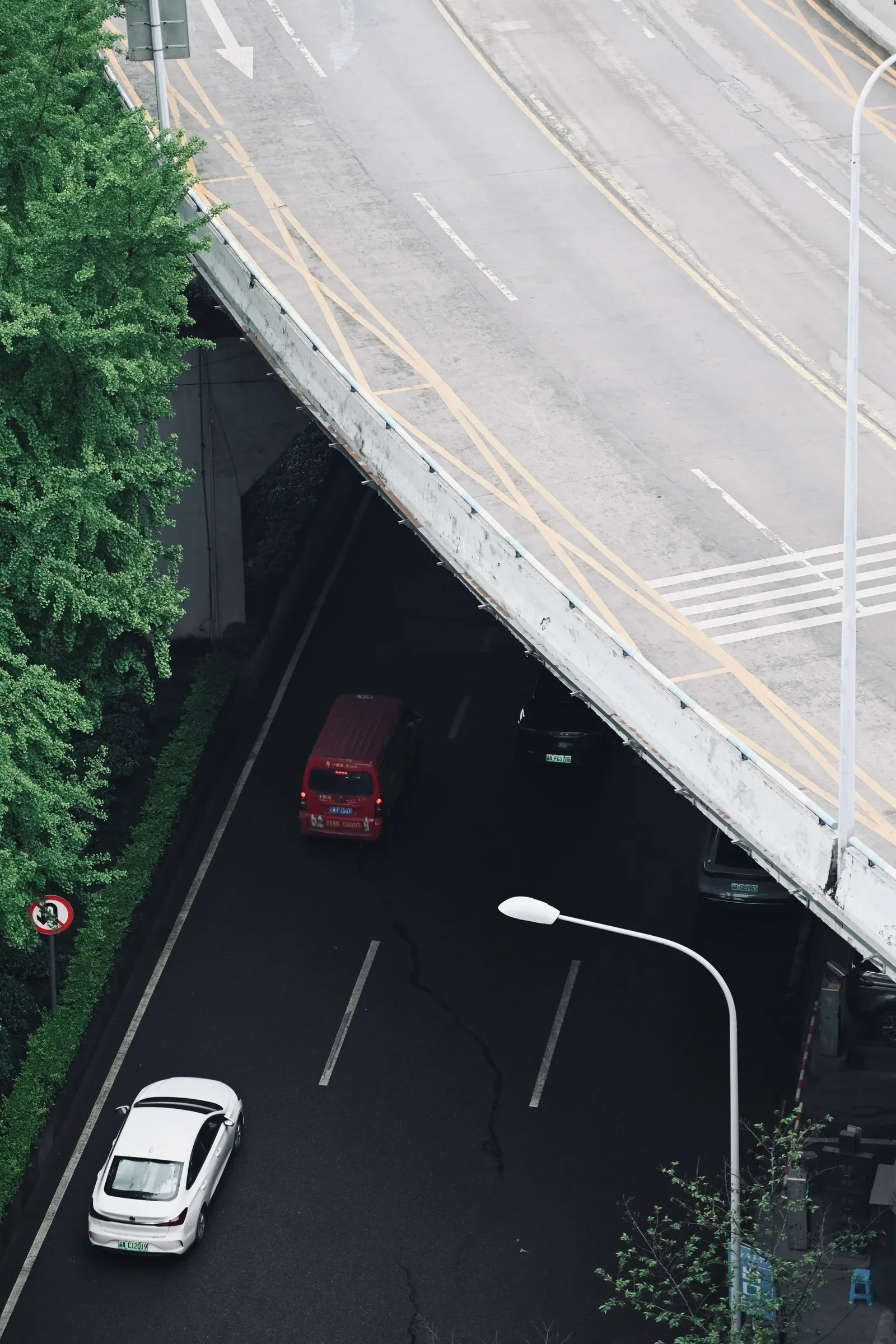 Cars pass beneath a sweeping elevated road viewed from above.